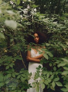 a woman standing in the woods with her arms crossed