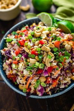 a bowl filled with rice and vegetables on top of a table next to lime wedges