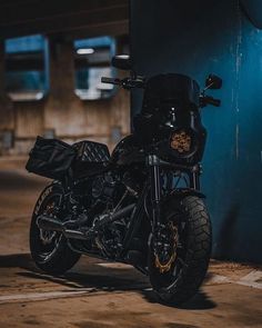 a black motorcycle parked next to a blue wall