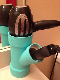 two cups with hair dryers in them sitting on a counter top next to a mirror