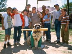 a group of young people posing for a photo with a dog holding a baseball bat