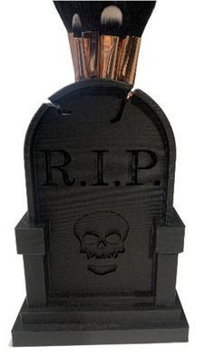 a black tombstone with makeup brushes in it