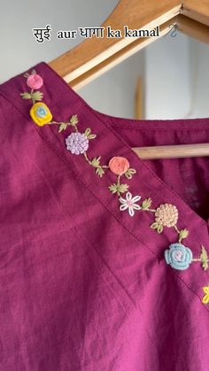 a close up of a dress with flowers and leaves on the side, hanging from a wooden hanger