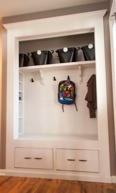 a white shelf with some black buckets on it and a coat rack in the middle