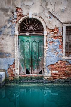 an old building with a green door in the water