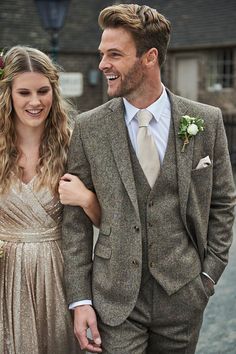 a man in a suit and tie standing next to a woman wearing a gold dress