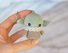 a hand holding a tiny crocheted yoda toy