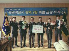 four men in suits and ties are holding up a sign while standing next to each other