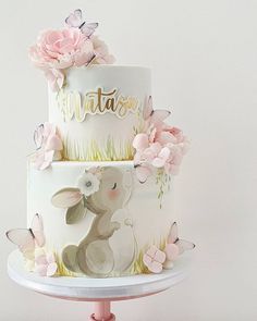 a three tiered cake decorated with pink flowers and an animal on the bottom layer