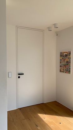 an empty room with two white doors and wood flooring on either side of the door