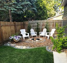 an outdoor fire pit surrounded by lawn chairs and flowers in the middle of a yard