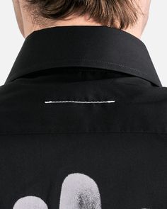 MM6 Maison Margiela Ultra Long Sleeve Shirt in Black. This long sleeve shirt features an exaggerated length with a pointed collar, front button closure, single chest pocket, embroidered MM6 logo on the front and a graphic on the back of the shirt. Modern Long Sleeve Shirt With Placket, Modern Shirt With Concealed Placket For Work, Designer Long Sleeve Shirt With Button Closure, Designer Black Shirt With Button Cuffs, Designer Long Sleeve Shirt With Placket, Designer Long Sleeve Business Tops, Designer Long Sleeve Office Shirt, Designer Long Sleeve Shirt For Office, Black Long Sleeve Top With Concealed Placket