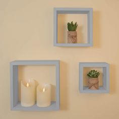 three white square shelves with candles and succulents