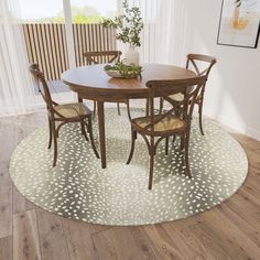 a dining room table with four chairs and a rug on the floor