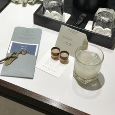 a table topped with two glasses filled with liquid next to a card and bottle opener