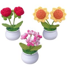 three crocheted flowers in white vases with green leaves and pink, red, yellow and white flowers