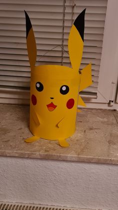 a paper cup with a pikachu face on it sitting in front of a window