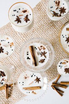 cinnamon sticks and star anise on top of small desserts in glass dishes with spoons