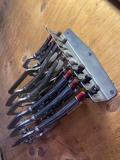 a bunch of knives are stacked on top of each other in a metal holder that is attached to a wooden table