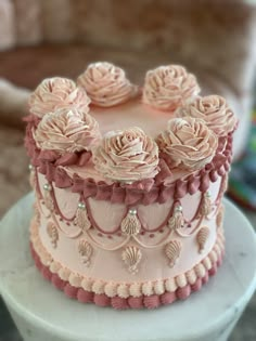 a three layer cake with pink frosting roses on it's side and beading around the edges