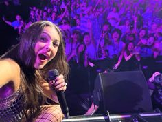 a woman singing into a microphone in front of a crowd