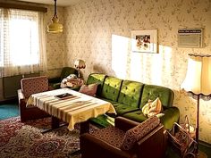 a living room filled with green couches next to a table and lamp on top of a rug