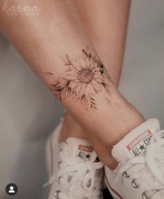 a woman's leg with a sunflower tattoo on it and white sneakers underneath