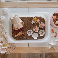 there are many seashells in the tray on the table and one is made out of sand