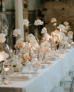 a long table is set with white flowers and candles for a formal dinner or reception