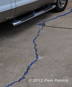 a white truck parked on top of a cement parking lot next to a blue rope