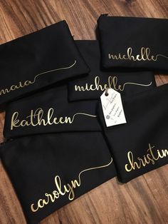 four personalized black and gold napkins with names on them sitting on a wooden table