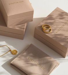 two gold rings sitting on top of each other next to a pair of jewelry boxes