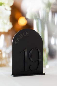 the table number is displayed in front of some vases with white flowers on it