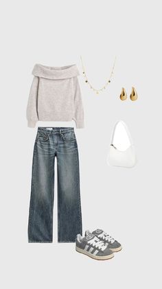 a pair of shoes, sweater and jeans are arranged on a gray background with gold accessories