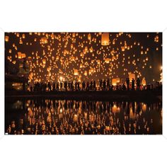 many lanterns are floating in the air over water at night with people standing around them