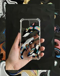 a hand holding up a clear case with colorful feathers on the front and back of it