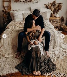 a man and woman sitting on top of a bed next to a baby