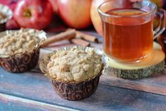 three muffins sitting on top of a wooden table next to a cup of tea