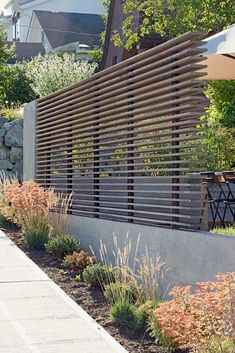 an outdoor area with plants, rocks and wooden slatted fence on the side