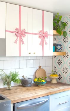 a kitchen with white cupboards and wooden counter tops, decorated with bows on the backs