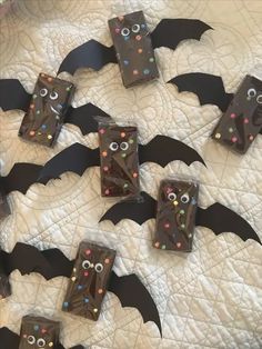 chocolate bats decorated with sprinkles and eyes on a white quilted surface