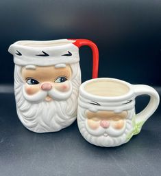 two coffee mugs with faces on them sitting next to each other in front of a black background