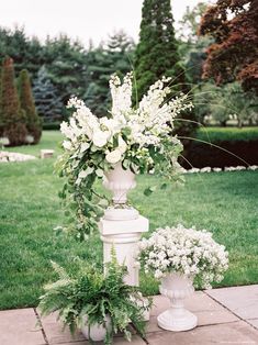 an instagram photo with flowers and greenery on the bottom right hand corner, in between two white urns