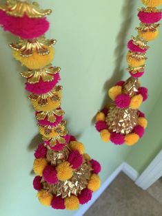 two yellow and pink pom poms hanging from the ceiling next to a green wall