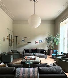 a living room filled with lots of furniture and a lamp hanging over the top of it