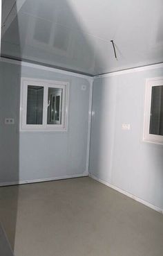 an empty room with two windows and no curtains on the walls, in front of a window