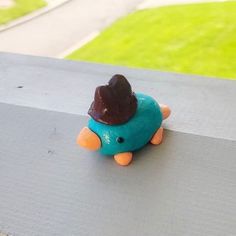 a small toy bird with a hat on top of it's head sitting on a ledge