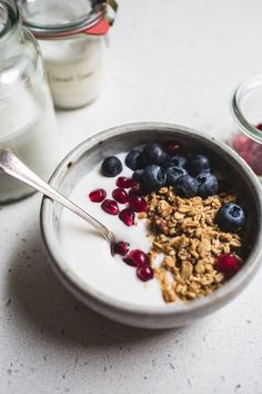 a bowl filled with granola and blueberries next to a glass of milk