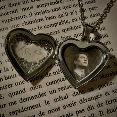 two heart shaped lockes with a man's face in it on top of an open book