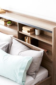 a bed with two pillows and a book shelf above it that has books on the shelves